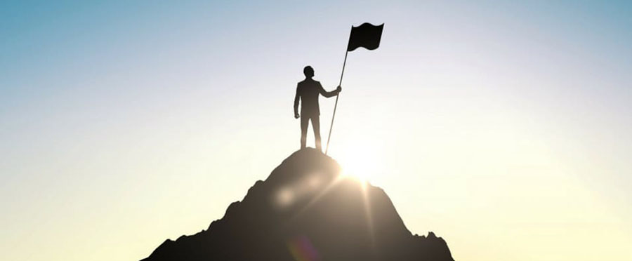 Мужчина на вершине горы с флагом